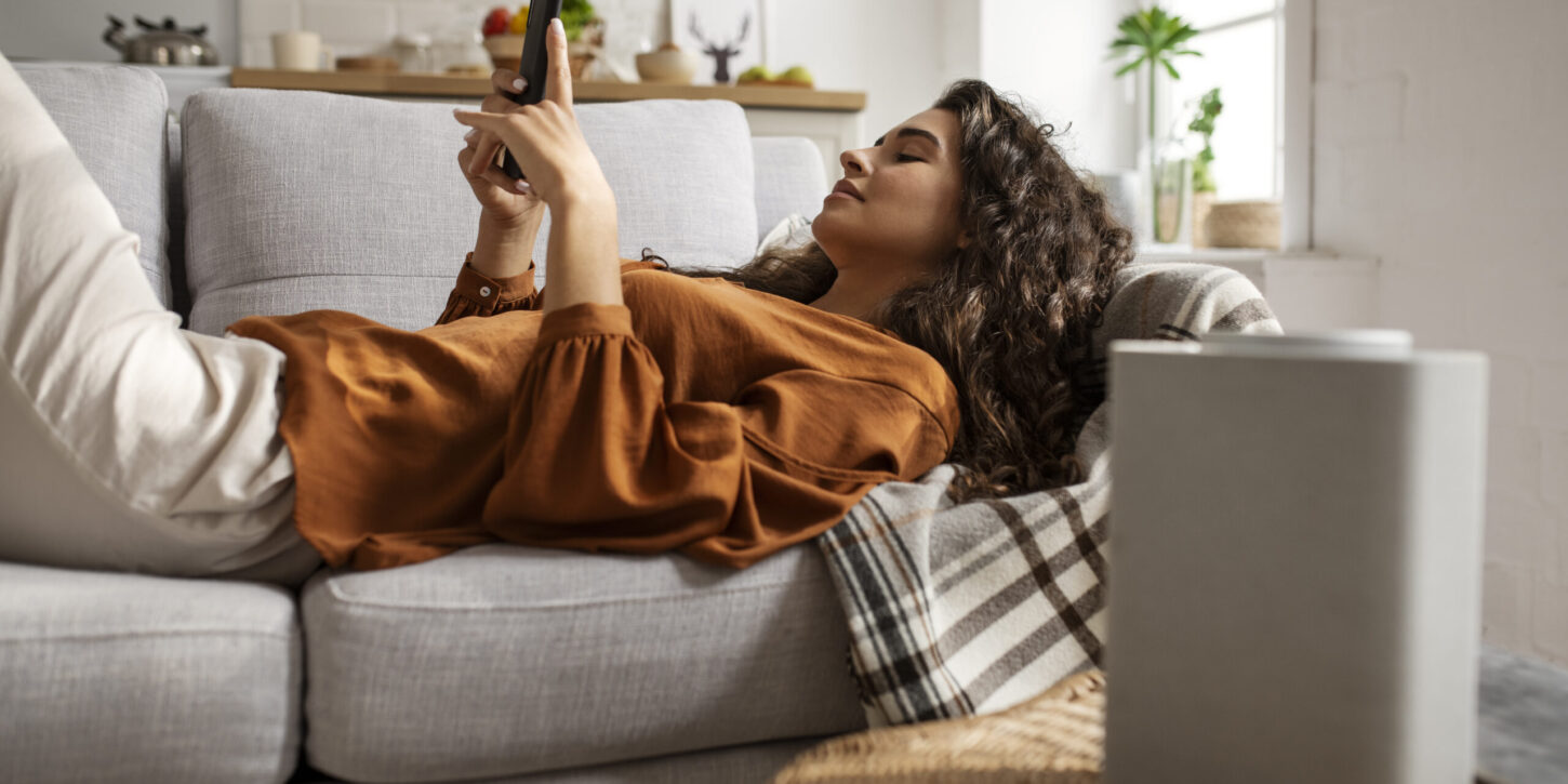 Los mejores Deshumidificadores para 2025. En la imagen aparece un chica tumbada en un sofá.