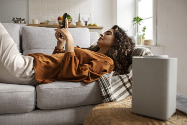 Los mejores Deshumidificadores para 2025. En la imagen aparece un chica tumbada en un sofá.